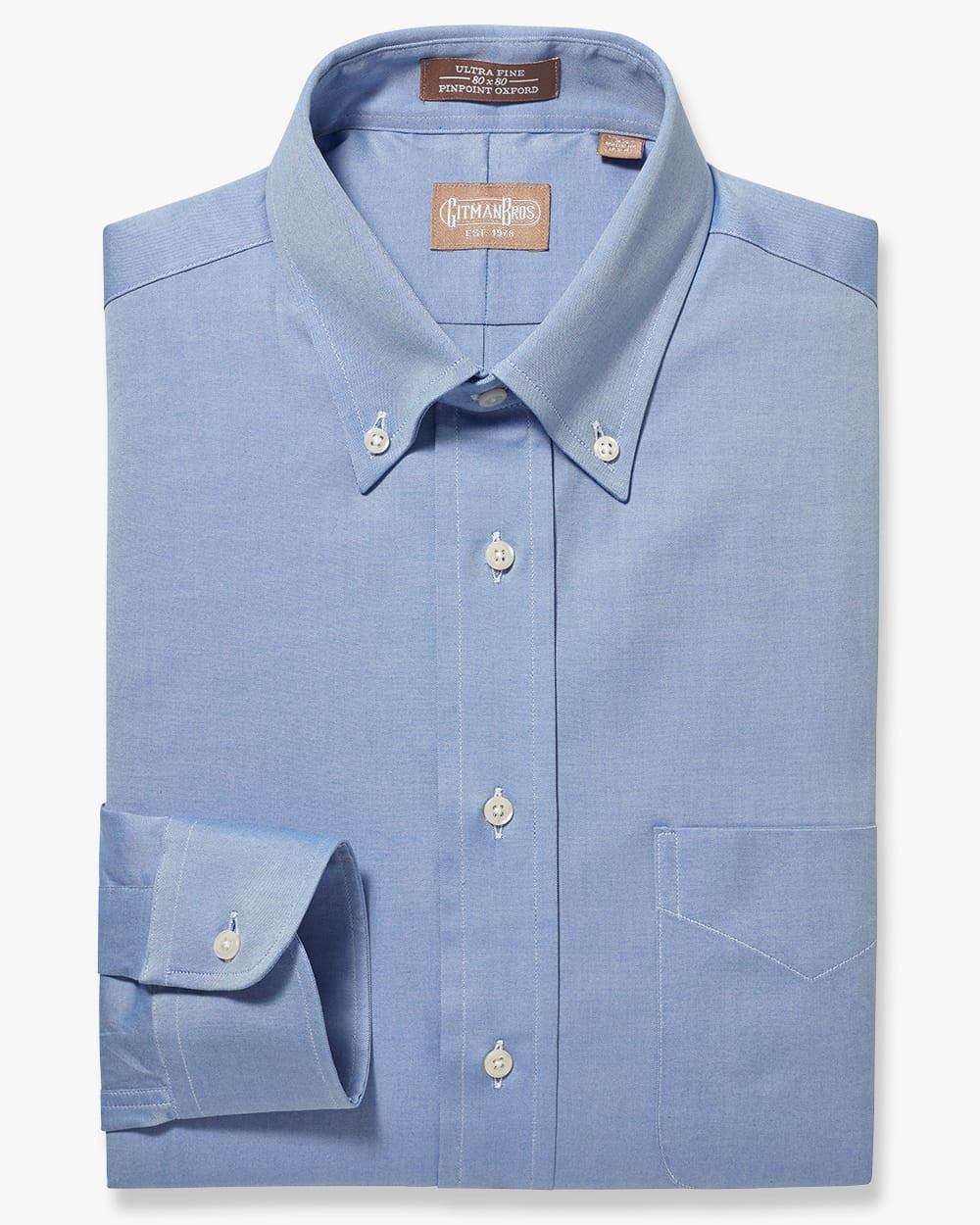 A folded button down shirt with white buttons made from solid blue pinpoint oxford cloth