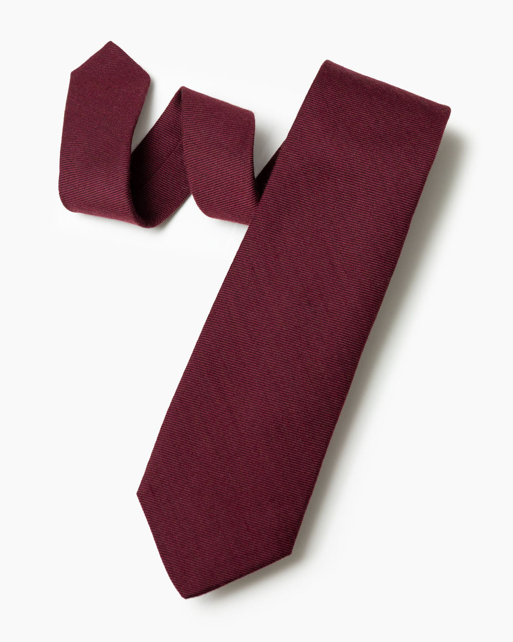 The burgundy wool/silk tie with 70% wool and 30% silk hand sewn labels, loops and bar tack with a hand shaped form.